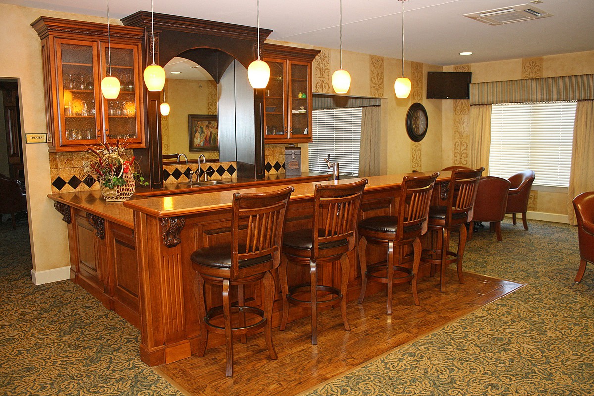 A cozy wooden bar with high chairs and ambient lighting.
