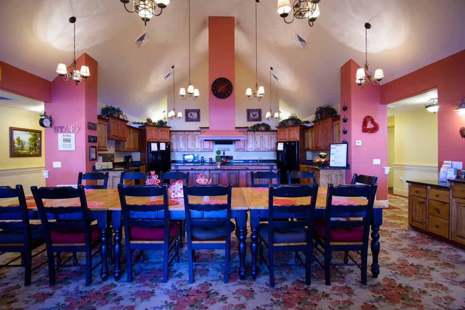 A spacious kitchen and dining area with high ceilings, featuring wooden furniture and chandeliers.
