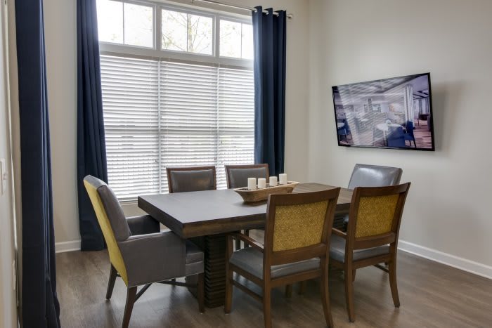 A modern dining room with a wooden table, chairs, large window, and wall art.