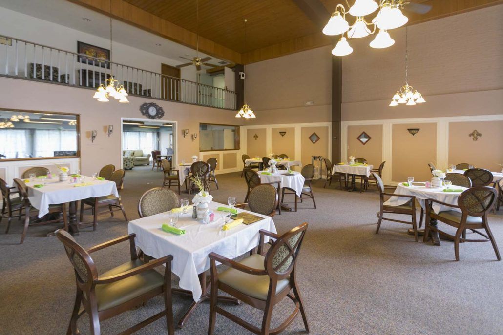 A cozy dining room with neatly arranged tables and chairs, featuring warm lighting and classic decor.