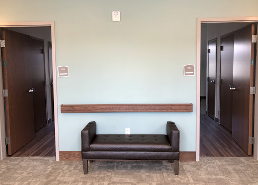 A waiting area featuring a simple bench between two doorways, with a soothing wall color.