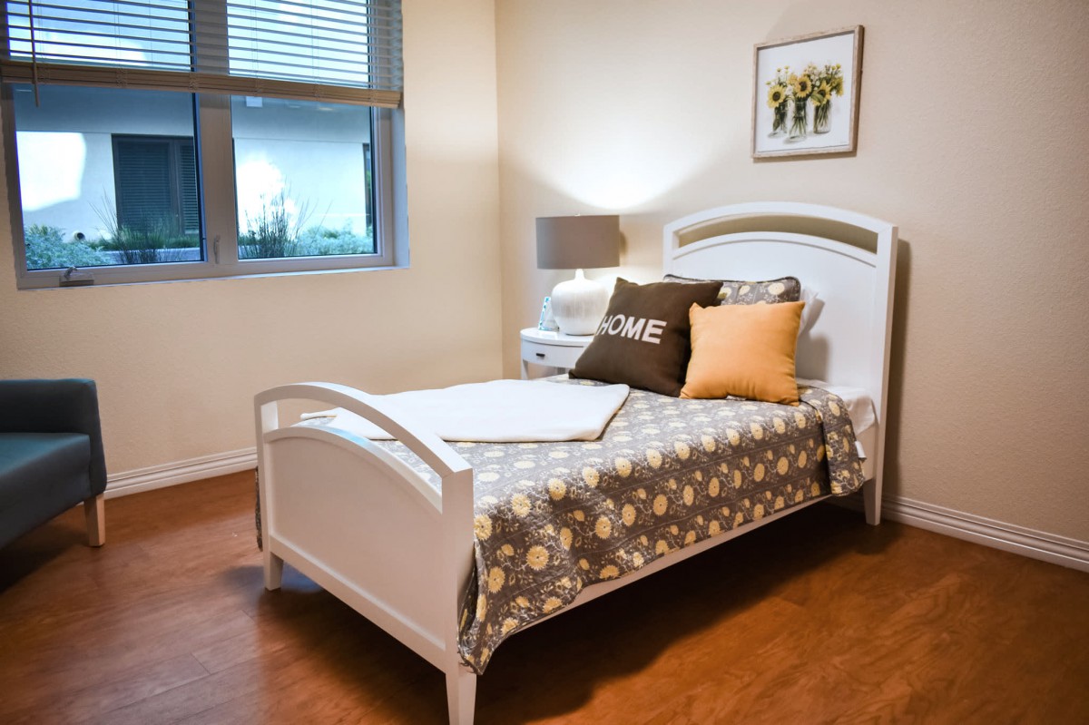 A cozy bedroom with a single bed, decorative pillows, and warm lighting.
