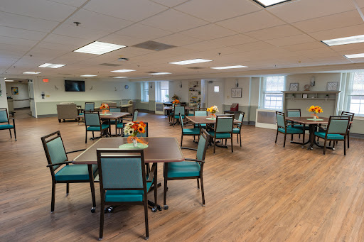 A spacious and well-lit dining area with tables and chairs arranged for communal activities.
