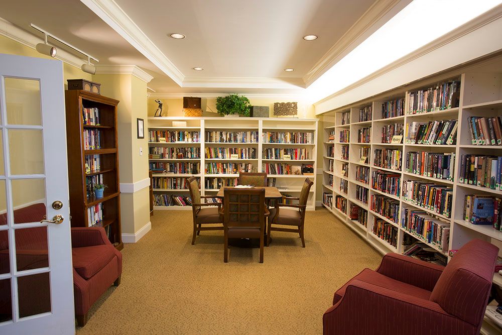 A cozy library with bookshelves, a table, and chairs arranged for reading.