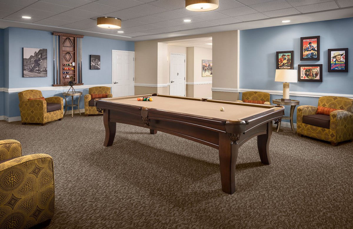 A cozy game room featuring a pool table and dartboard, surrounded by comfortable seating.