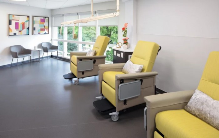 A modern clinic waiting area with comfortable yellow recliner chairs and large windows.