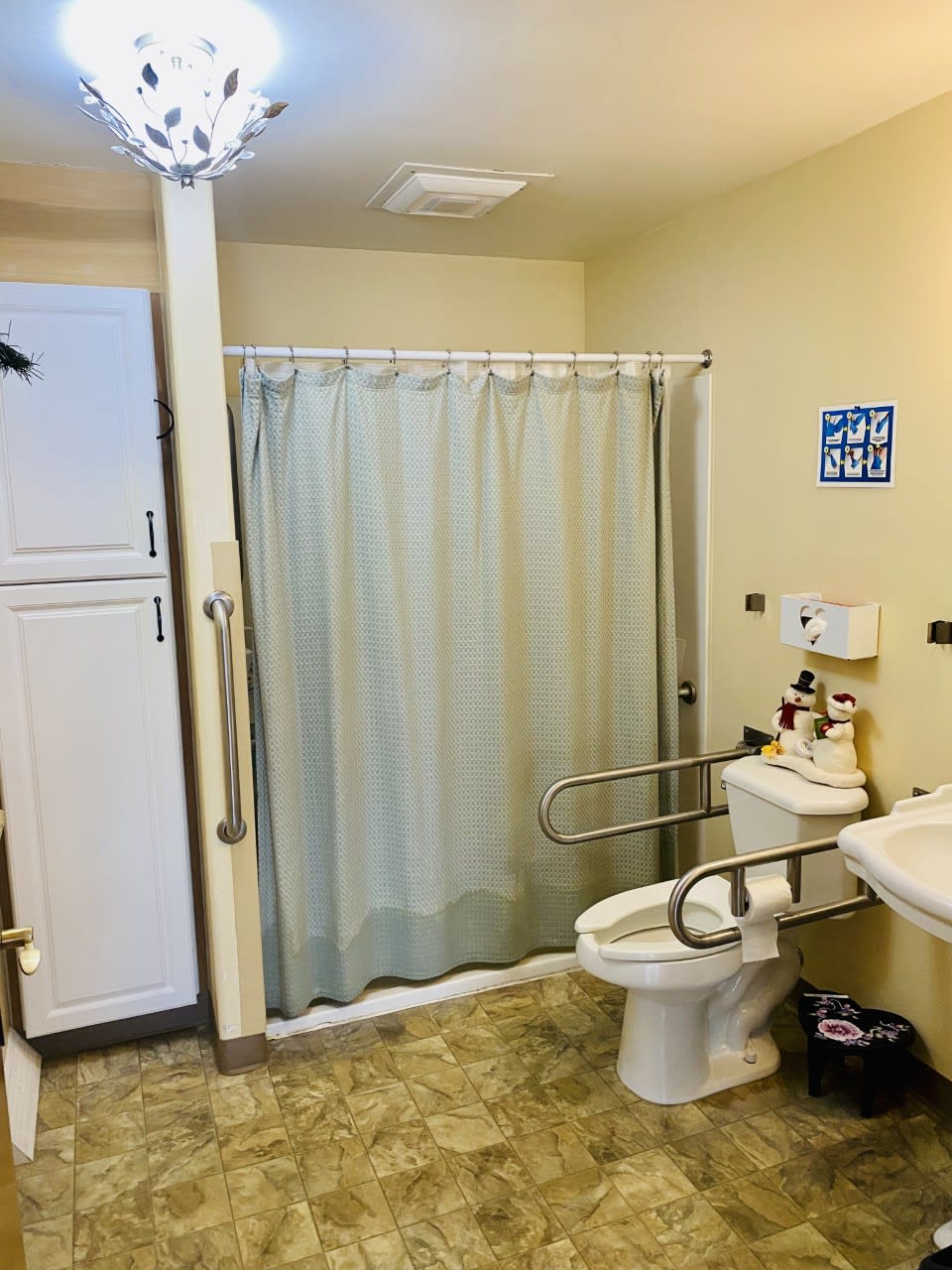 An accessible bathroom with grab bars, a shower curtain, and a toilet.