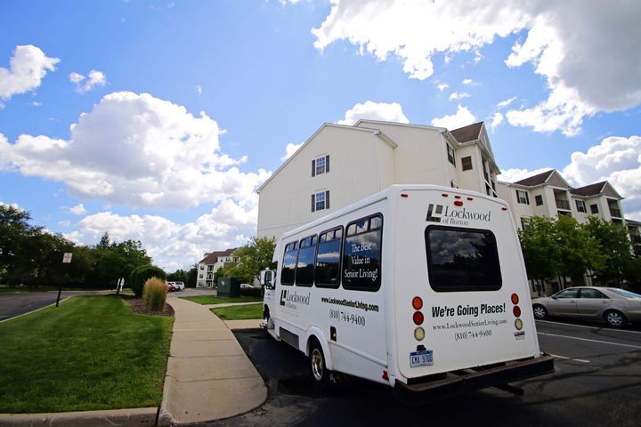 A shuttle bus parked in a residential area under a cloudy sky.
