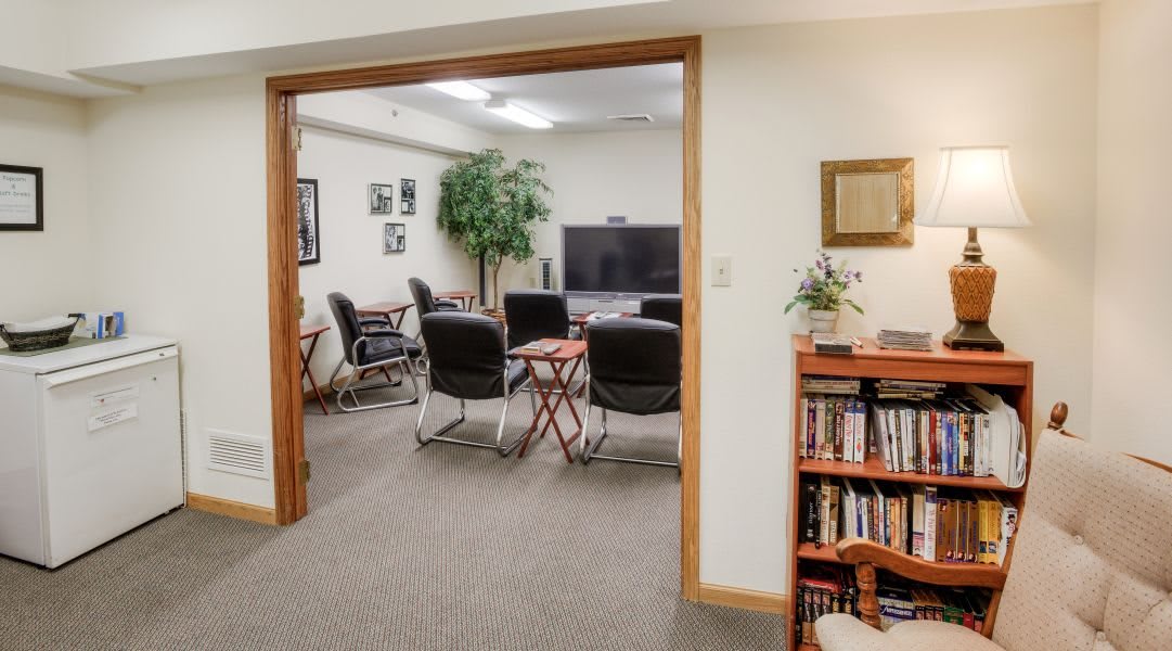 A small office conference room with a television, chairs, and a bookshelf.