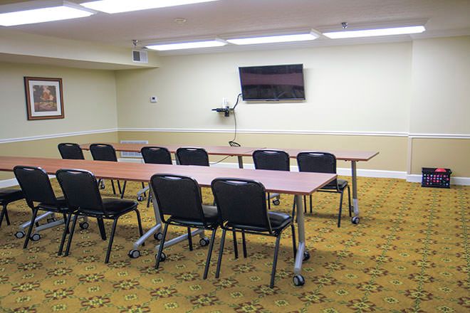 A modern conference room equipped with tables, chairs, and a large television for presentations.