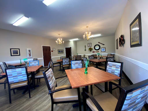 A well-decorated dining area with neatly arranged tables and chairs, featuring indoor lighting and wall decor.