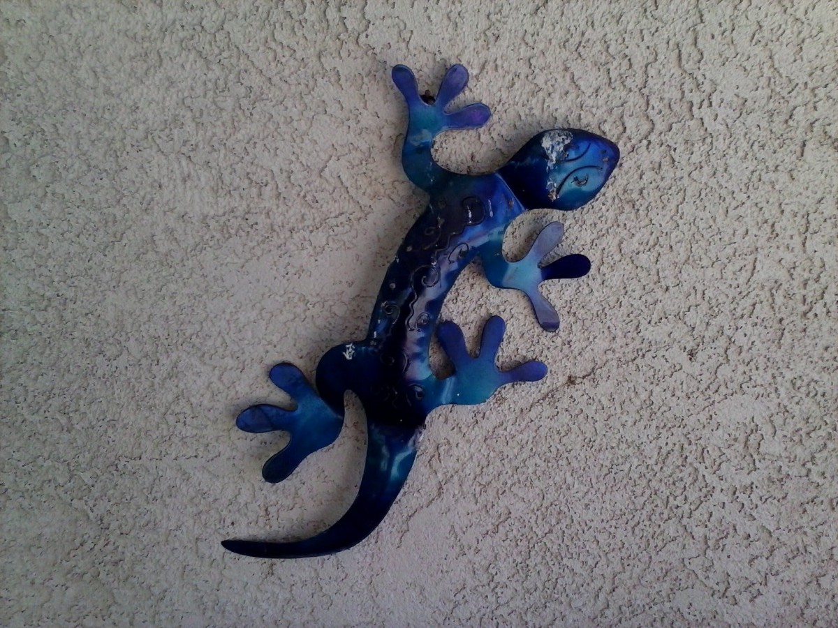 Blue decorative metal lizard hanging on a wall.