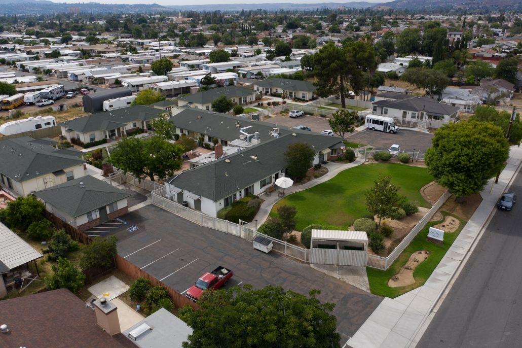 Aerial view of a residential neighborhood with green spaces and parking lots.