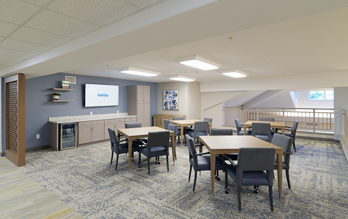 A modern conference room with tables, chairs, and a large screen.