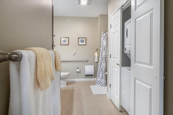 A modern bathroom with a washer-dryer, featuring neutral tones and simple decor.