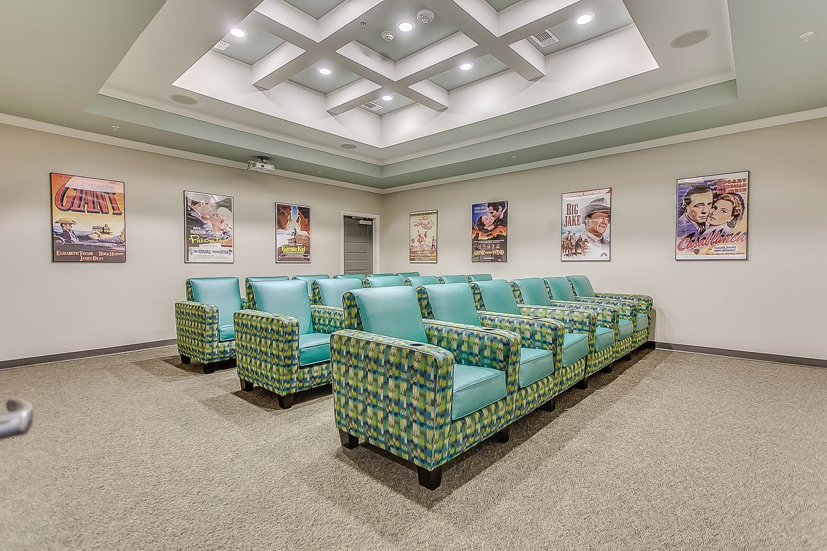 A small theater room with patterned seating and movie posters on the walls.