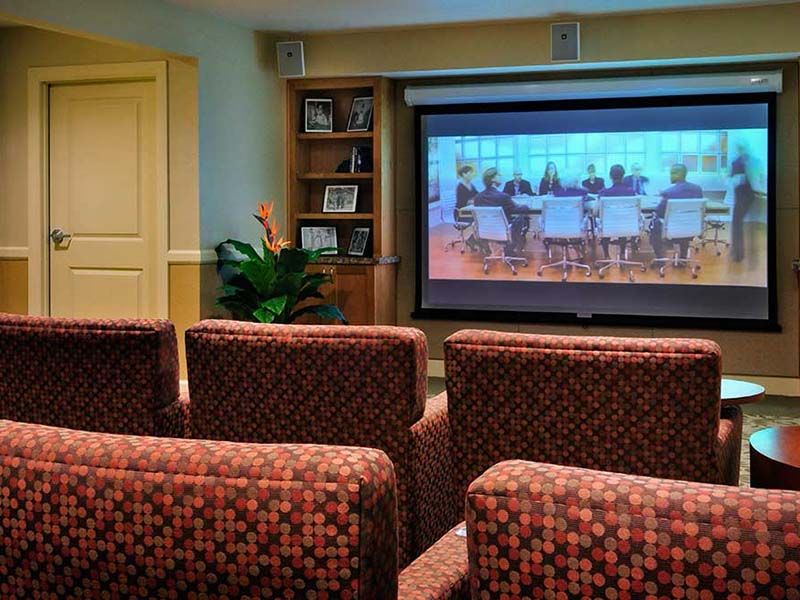A cozy home theater room with patterned seating and a large screen displaying a movie.