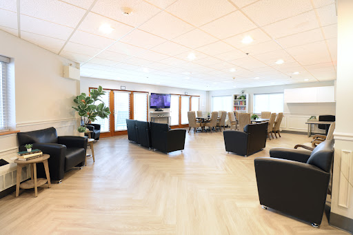 A modern lounge area featuring comfortable seating, a television, and large windows that provide ample natural light.