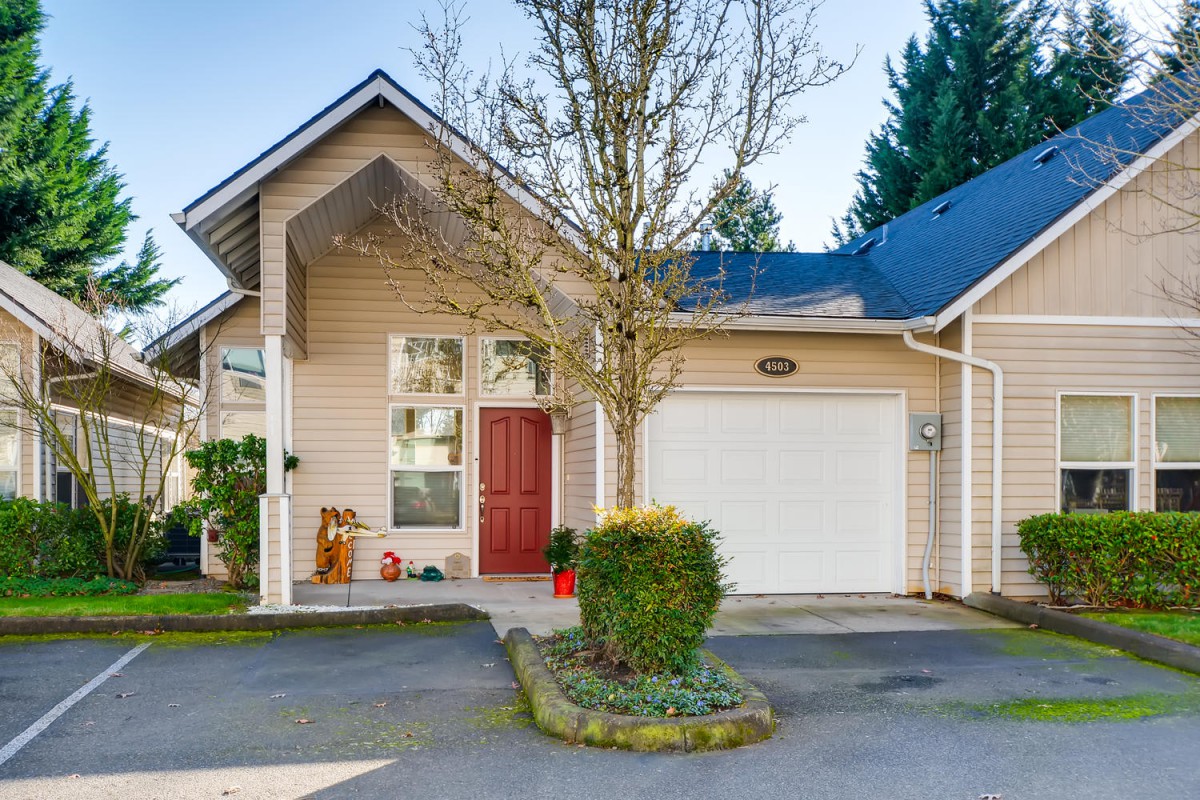 A modern residential house with a garage and small tree in the front yard.