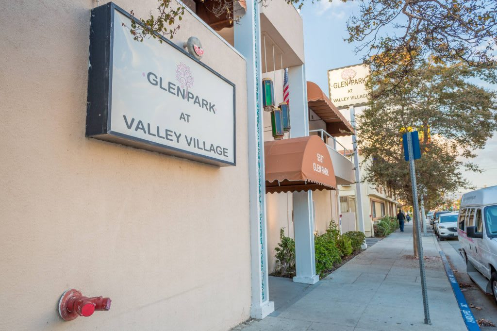 A view of the Glenpark at Valley Village apartment building with signage and sidewalk in the foreground.