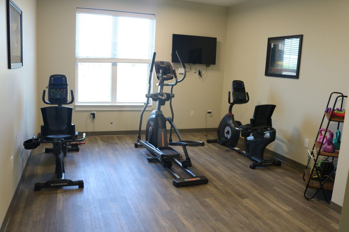 A small indoor gym with an elliptical trainer and stationary bikes.