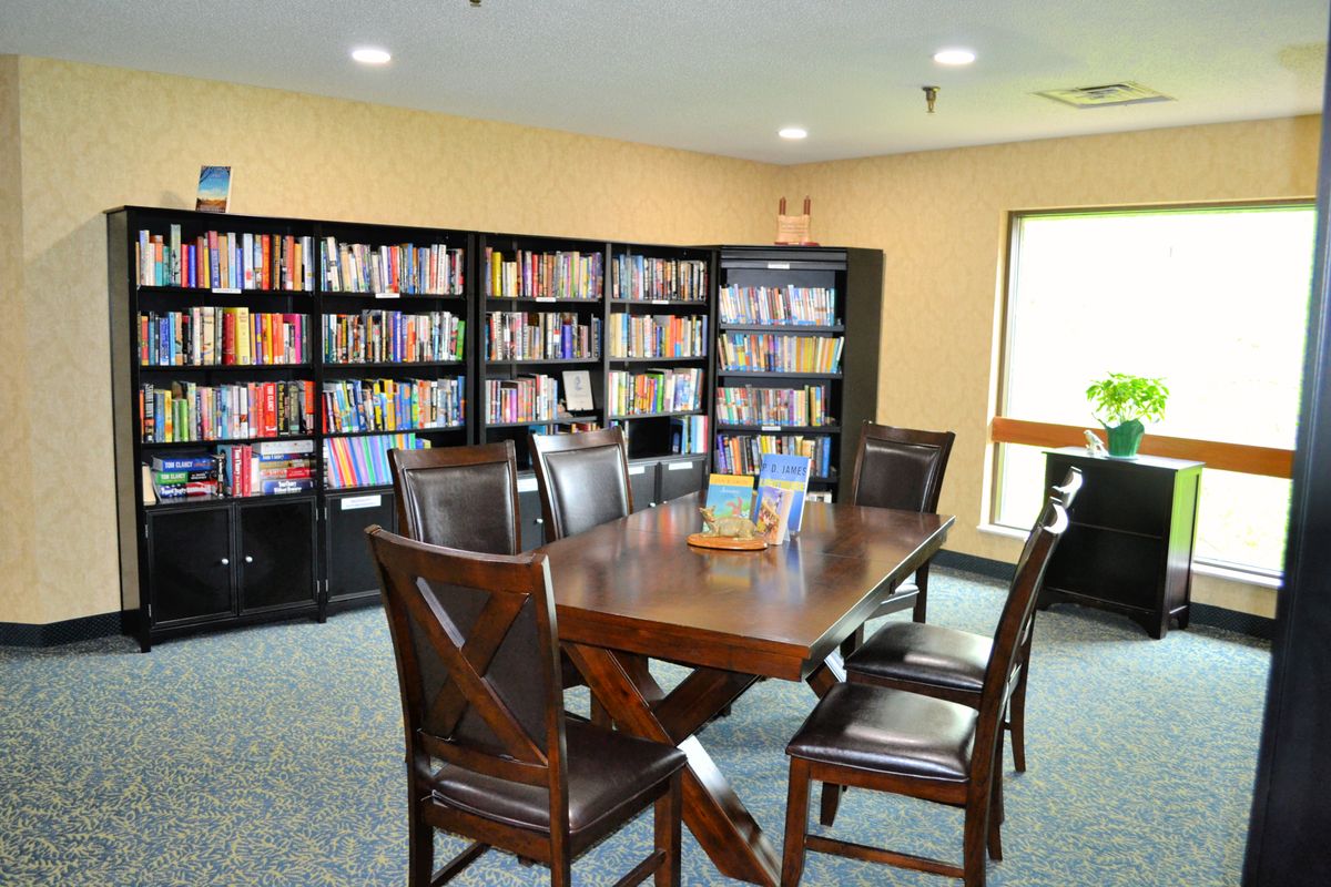 A cozy library reading area with a wooden table and chairs surrounded by bookshelves.