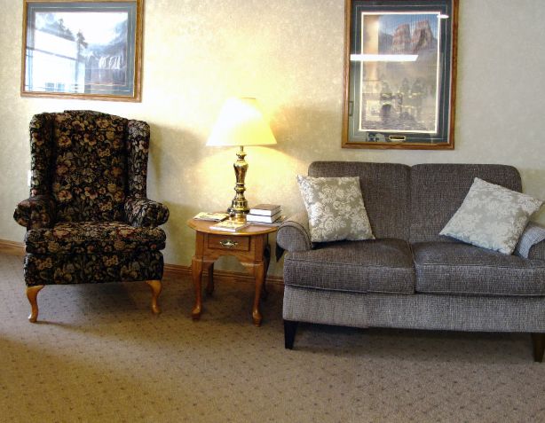 A cozy living room with a sofa, armchair, and a lamp on a side table.