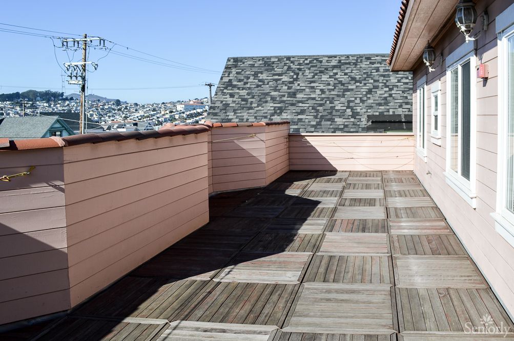 A sunny rooftop terrace with tiled flooring and a view of the skyline.