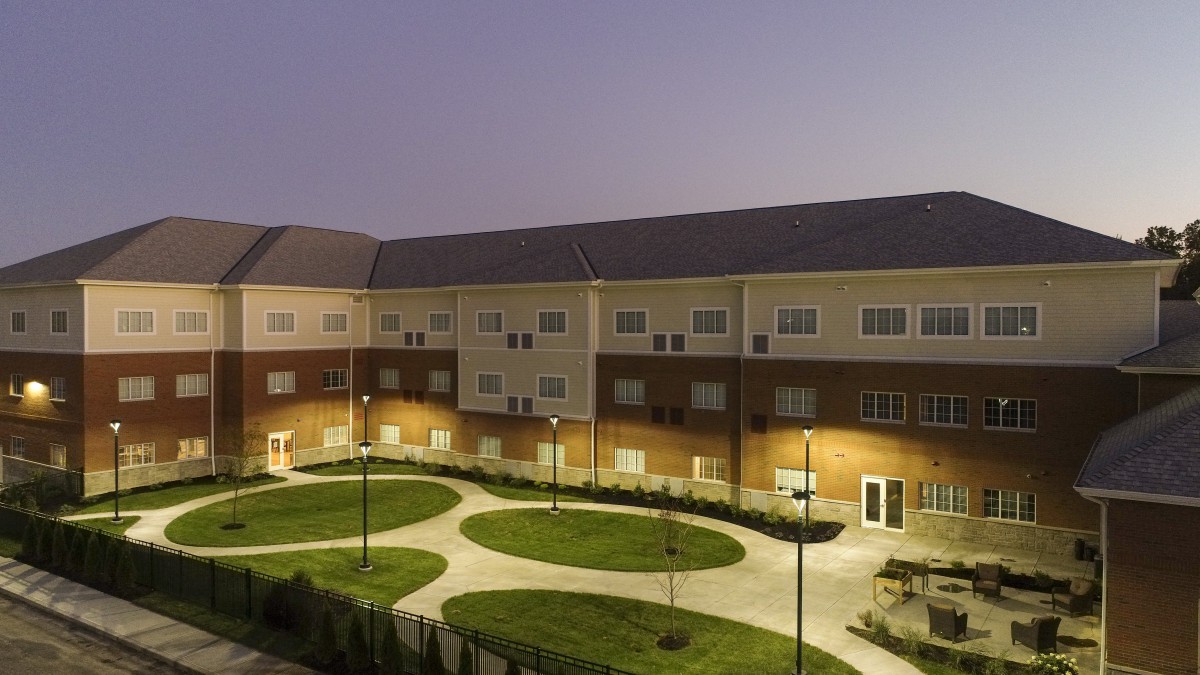 A well-lit residential building with a landscaped courtyard at night.