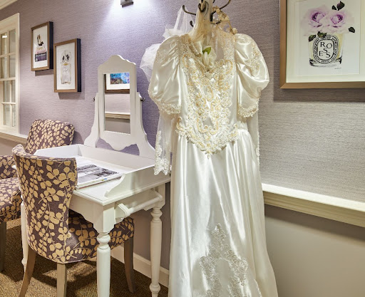 A beautiful bridal gown displayed in an elegant bedroom setting.