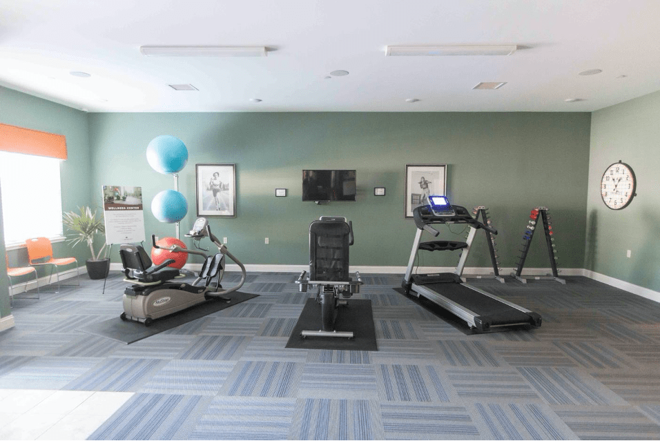 A modern gym with various exercise equipment including a treadmill, stationary bike, and exercise balls.