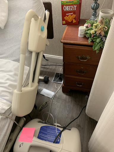 A snapshot of a bedroom corner featuring a nightstand, medical equipment, and visible cables.