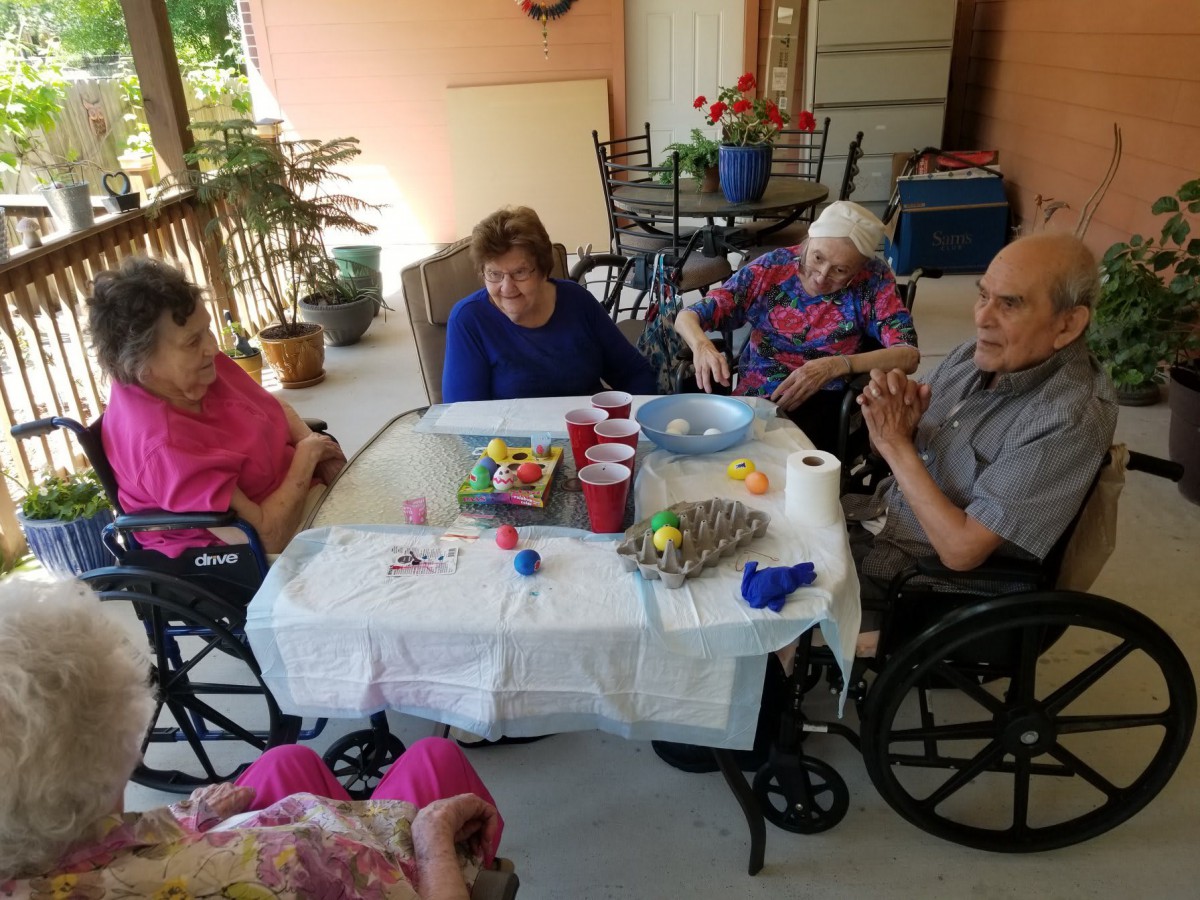 A group of elderly individuals sitting around a table outdoors, enjoying each other's company.