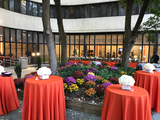 A vibrant outdoor setting featuring colorful flower beds and neatly arranged tables, perfect for an event.