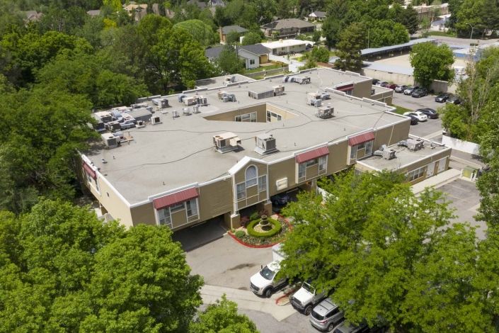 Aerial view of a commercial building surrounded by trees and a parking lot.