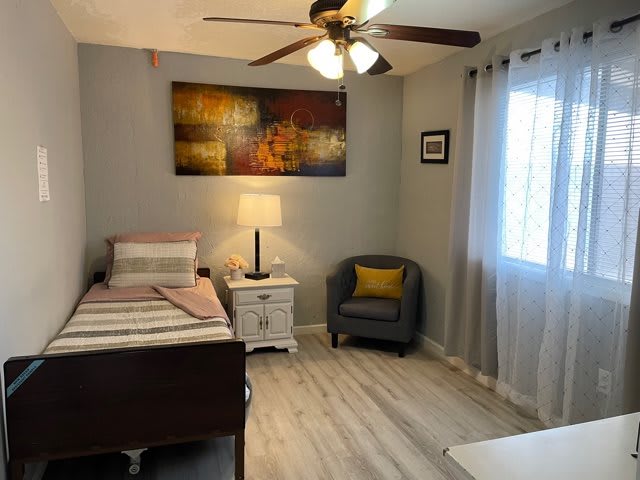 A cozy bedroom with a single bed, armchair, and stylish artwork on the wall.
