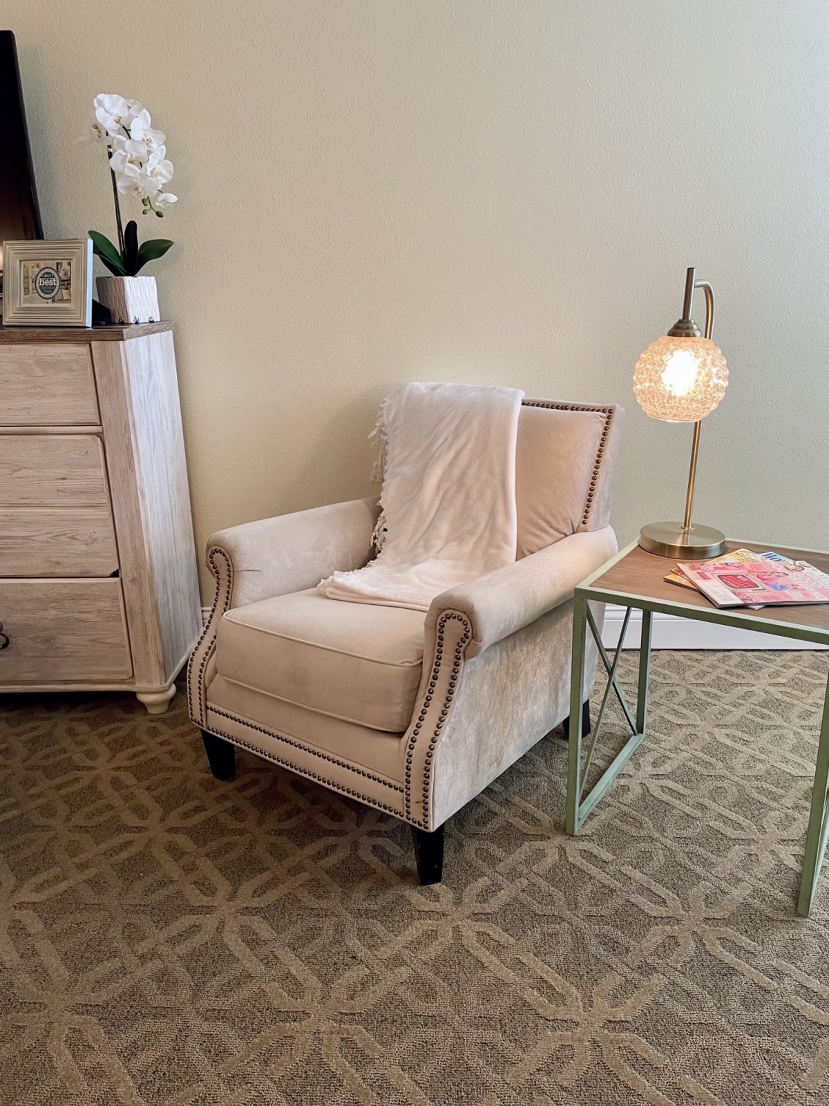 A cozy corner featuring a plush armchair, accented with a side table and lamp, perfect for relaxation.