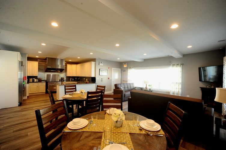 A cozy dining area with a wooden table set for a meal, adjacent to a modern kitchen.