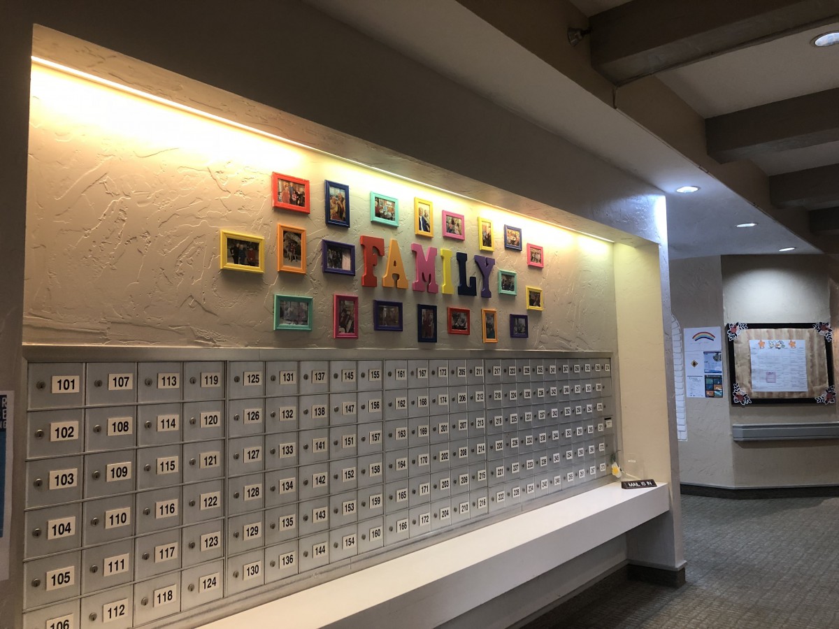 A hallway featuring a row of mailboxes beneath a colorful art display on the wall.