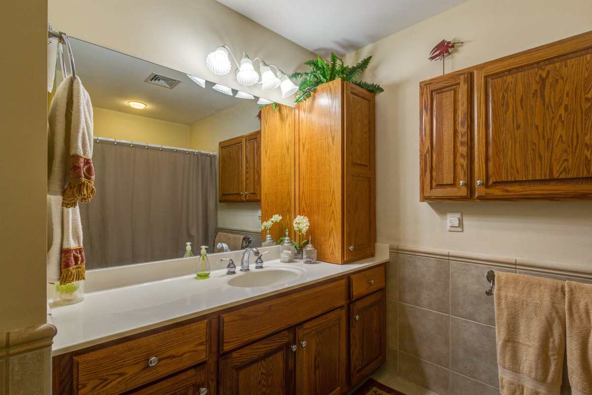 A bathroom with a large mirror, wooden cabinets, and modern fixtures.