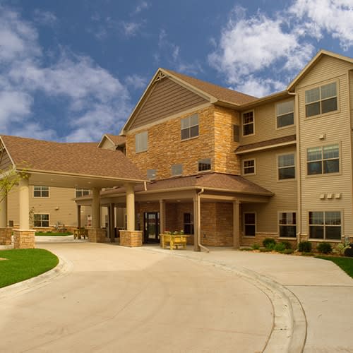 A modern residential building with a welcoming driveway under a clear blue sky.