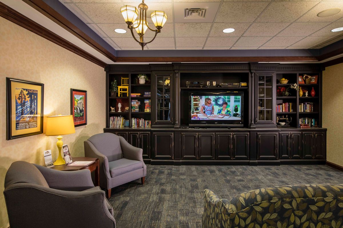 A cozy living room featuring a television, comfortable seating, and built-in bookshelves.
