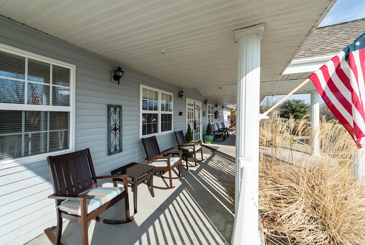 A cozy porch with chairs and a bench, featuring columns and an outdoor seating area.