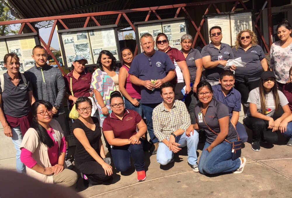 A group of people posing for a photo outside on a sunny day.