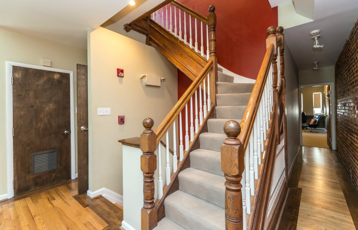 A wooden staircase with carpeted steps and decorative banisters in a home interior.