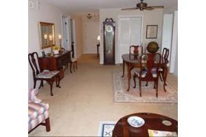 A traditional living and dining area featuring a wooden dining set, grandfather clock, and classic decor elements.
