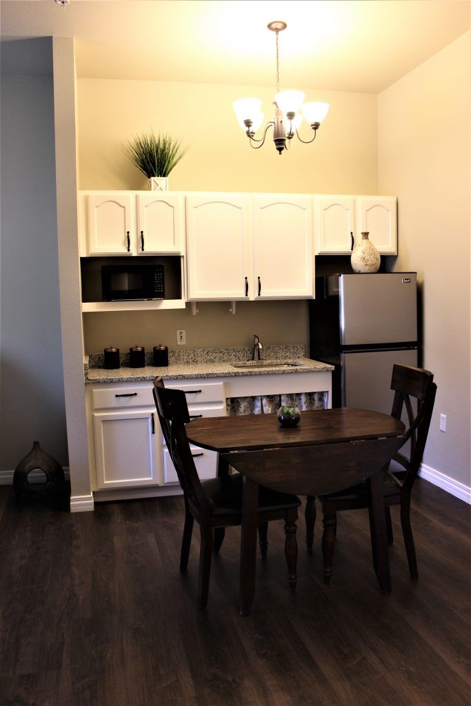 A cozy kitchen and dining area with white cabinets, a round table, and modern appliances.