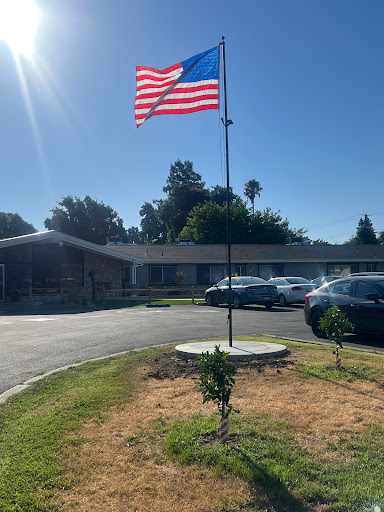An American flag waving proudly on a flagpole in front of a building during a sunny day.