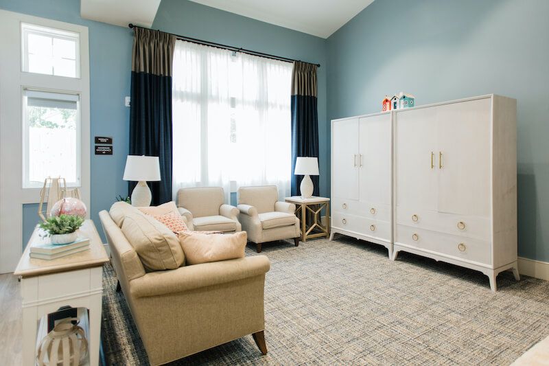 A cozy and elegantly designed living room with a sofa, armchairs, and large windows.