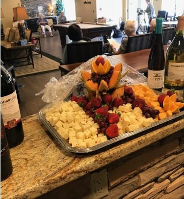A beautifully arranged fruit and cheese platter accompanied by bottles of wine in a cozy dining setting.